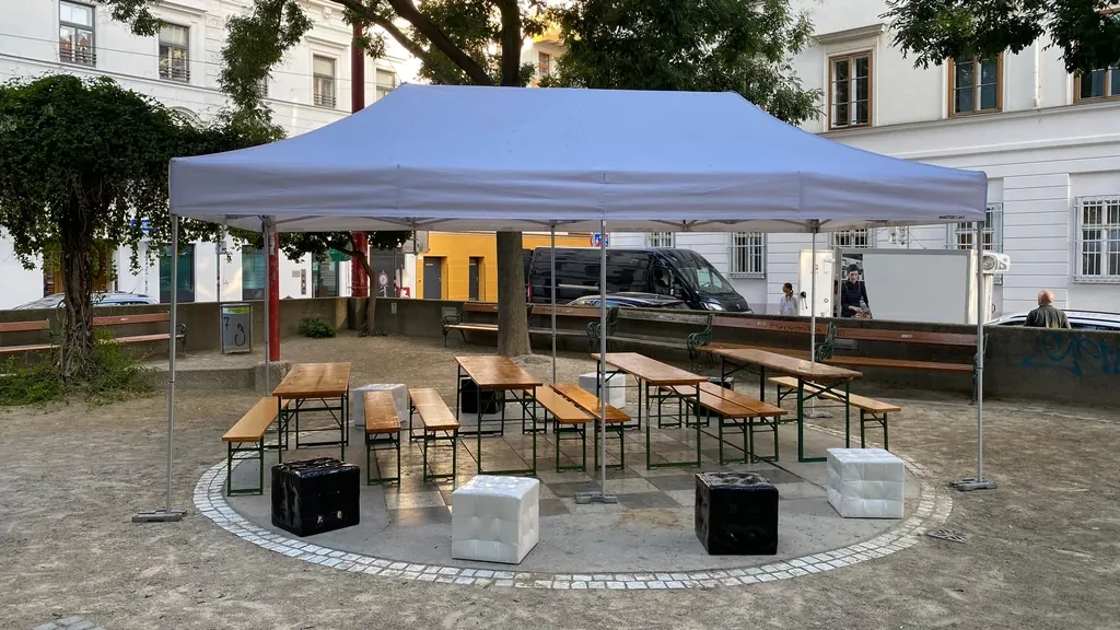 Faltzelt mit Bierbänken und Sitzwürfeln auf einem Platz
