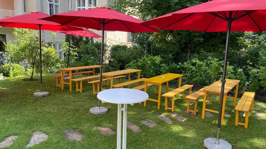 Sonnenschirme, Bierbänke und Stehtisch in einem Wiener Innenhofgarten
