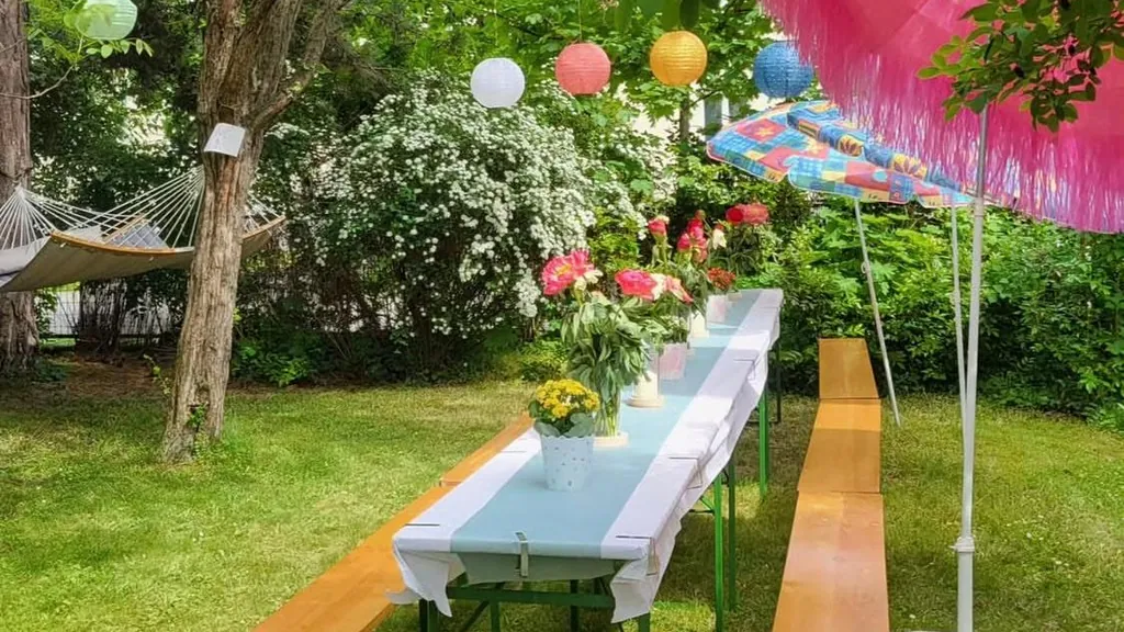 Gedeckte Festtafel mit Blumen und Lampions bei einem Gartenfest